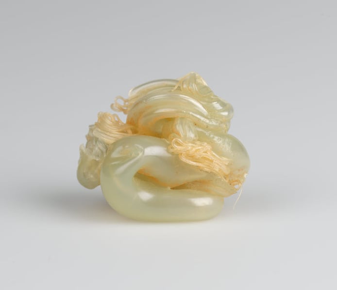 Curled piece of yellowed plastic with smaller curly pieces of plastic woven around it.