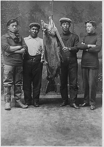 Four unidentified young Indian men with large salmon.