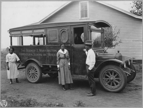 Black and white photograph of a bookmobile with 2 women and one man standing to the side of the truck