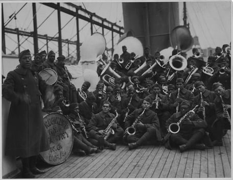 Black and white photograph of a group of soliders aboard a ship playing instruments