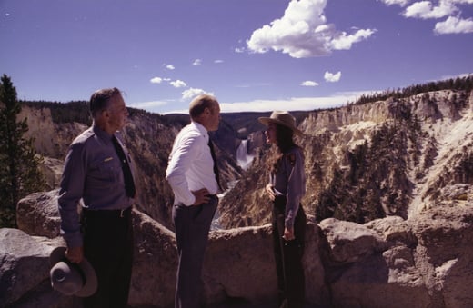 President Gerald Ford speaks with park rangers at an overlook in Yellowstone National Park. The mountains can be seen in the background.