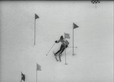 Animated GIF of a person skiing down a hill, weaving through poles