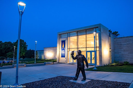 Entrance to the Truman Library.  A statue of President Truman stands at the entrance, and the lights from inside the building can be seen