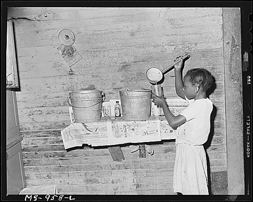 Daughter of Carlos Wilson, miner, pours herself a drink of water. Consolidated Coal Company, Bankhead Mine, Bankhead, Walker County, Alabama. National Archives Identifier 540629